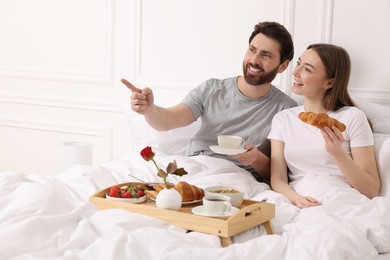 Photo of Happy couple having tasty breakfast in bed at home