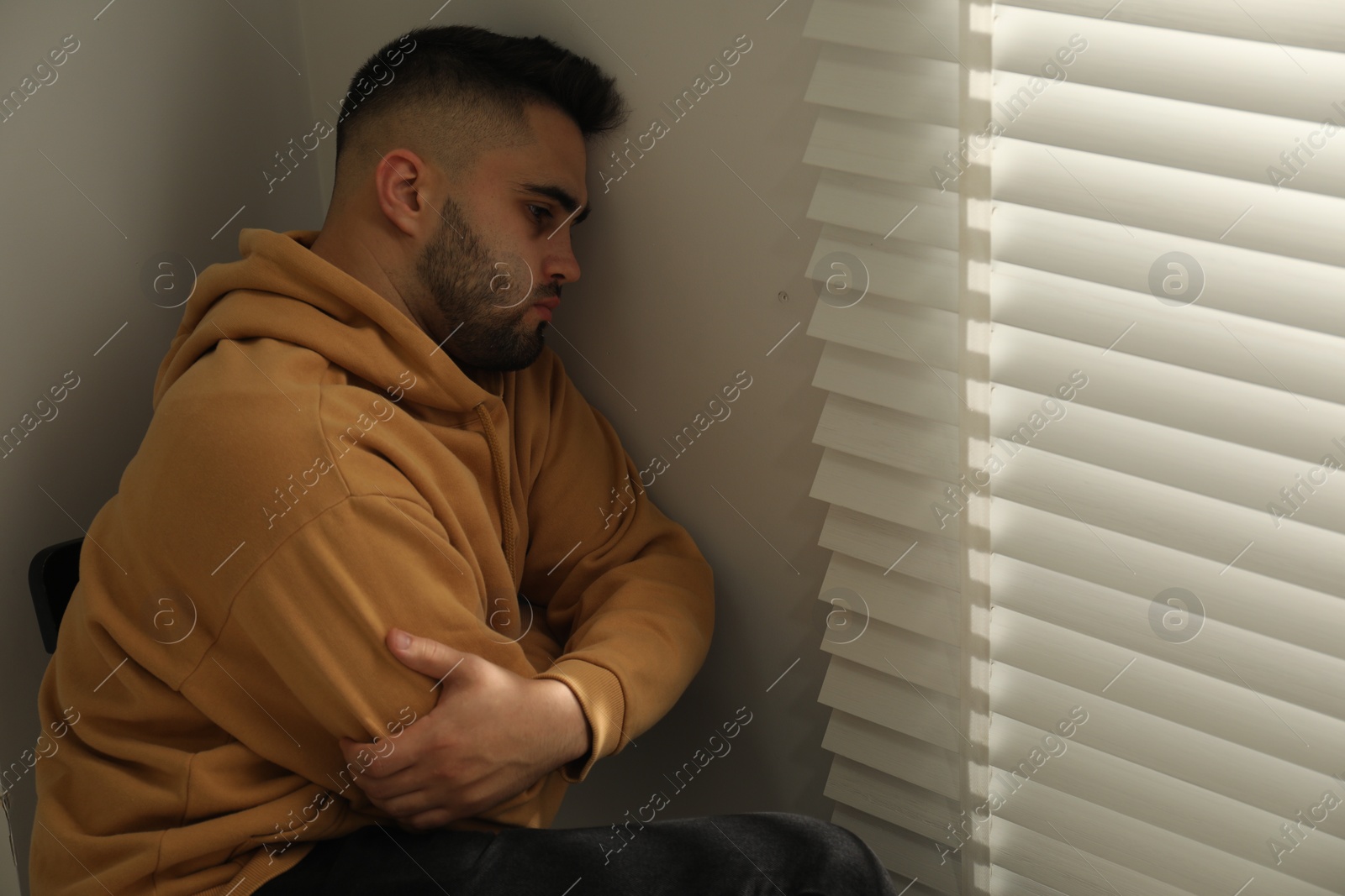 Photo of Sad young man and sitting near window