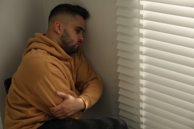 Photo of Sad young man and sitting near window