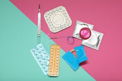 Photo of Contraceptive pills, condoms, intrauterine device and thermometer on color background, flat lay. Choice of birth control method
