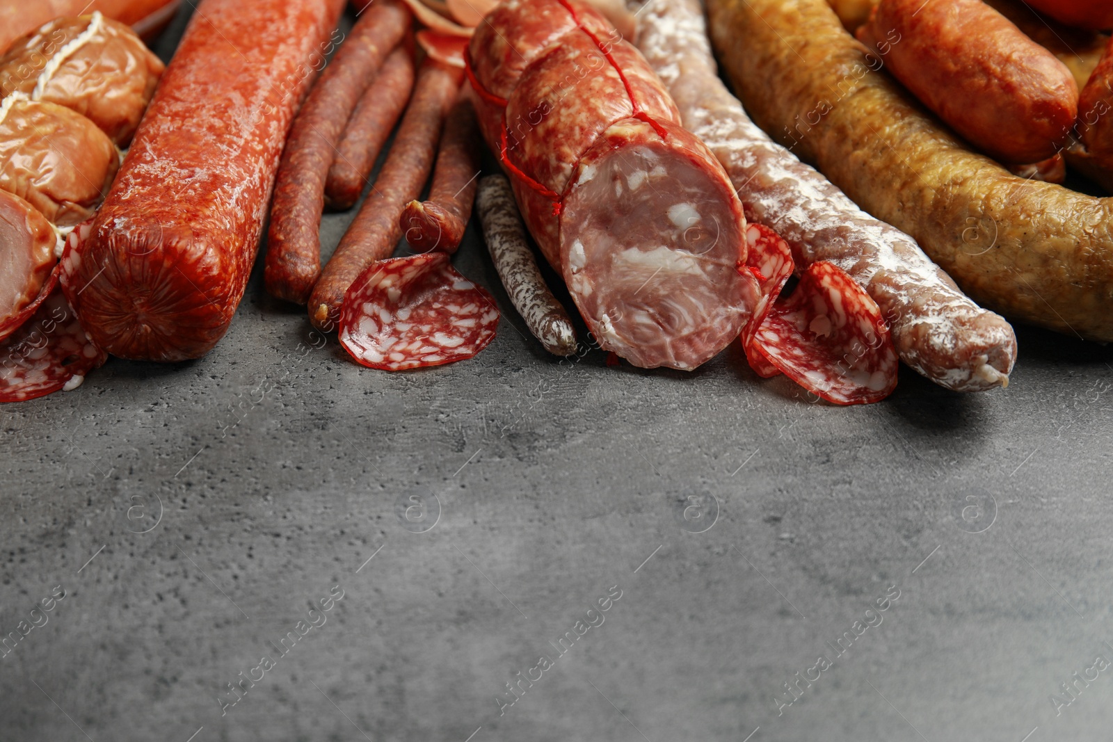 Photo of Different types of sausages on grey table. Space for text