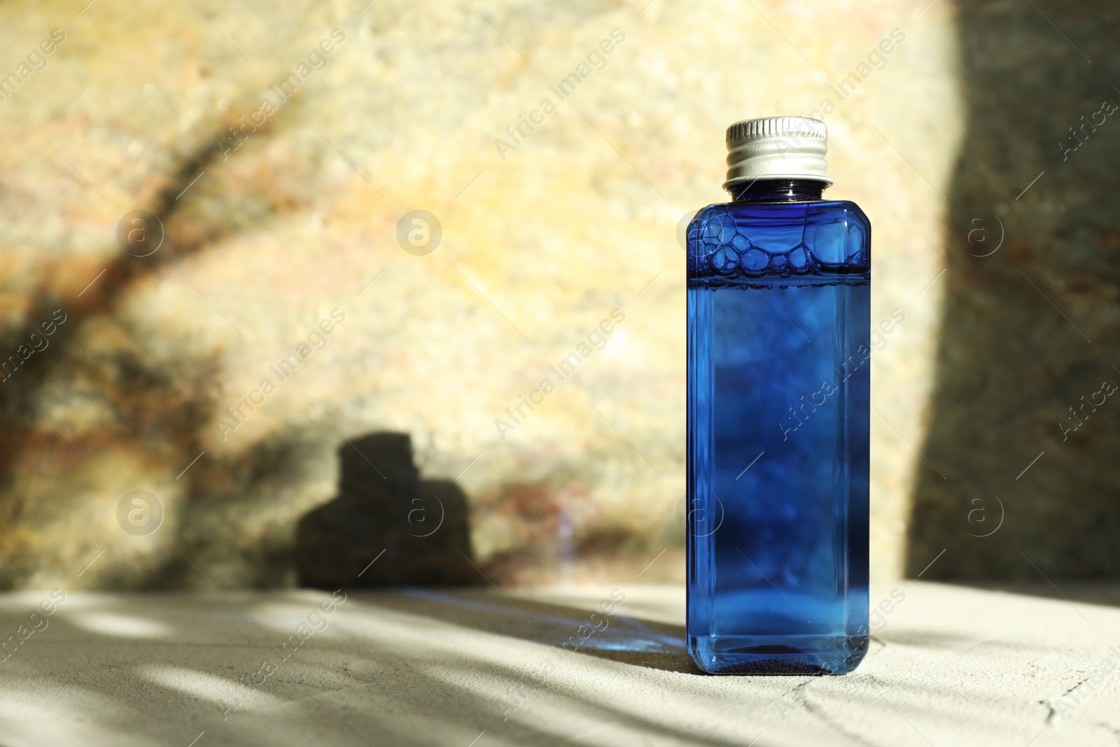 Photo of Cosmetic product in blue bottle on beige textured table. Space for text