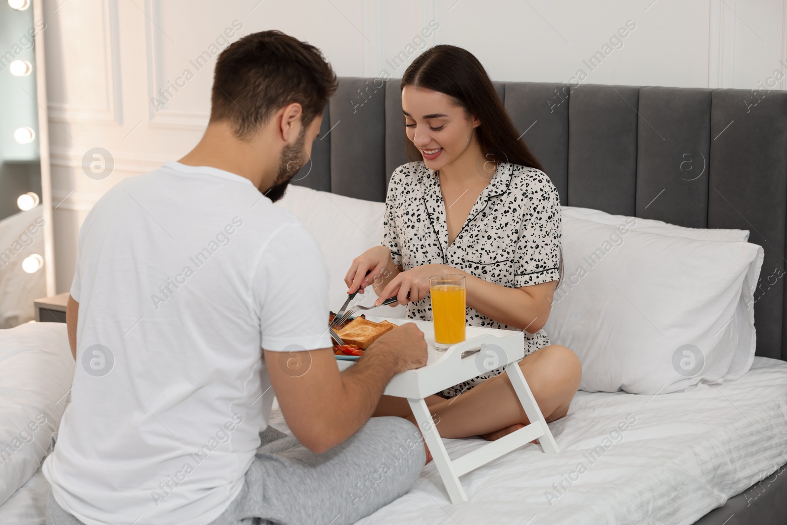 Photo of Happy couple having breakfast on bed at home