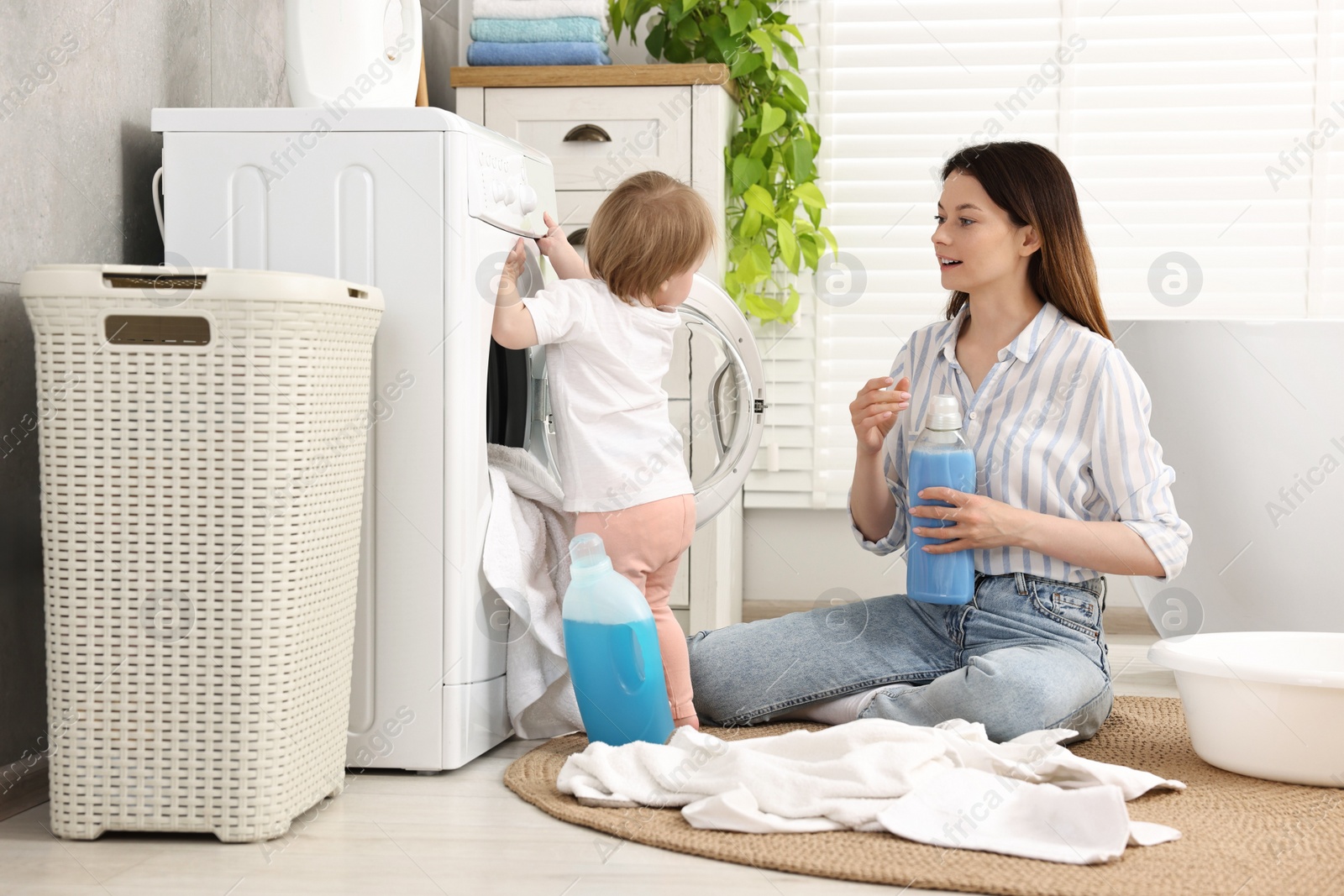 Photo of Mother with her daughter washing baby clothes in bathroom