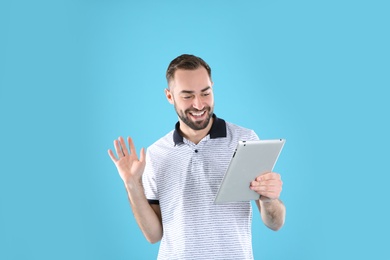 Man using tablet for video chat on color background