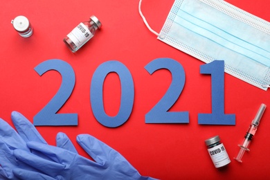 Photo of Flat lay composition with coronavirus vaccine and number 2021 on red background