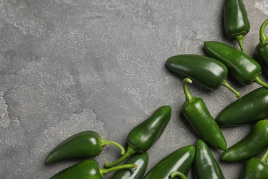 Green hot chili peppers on grey table, flat lay. Space for text