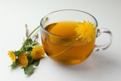 Photo of Delicious fresh tea and beautiful dandelion flowers on white background