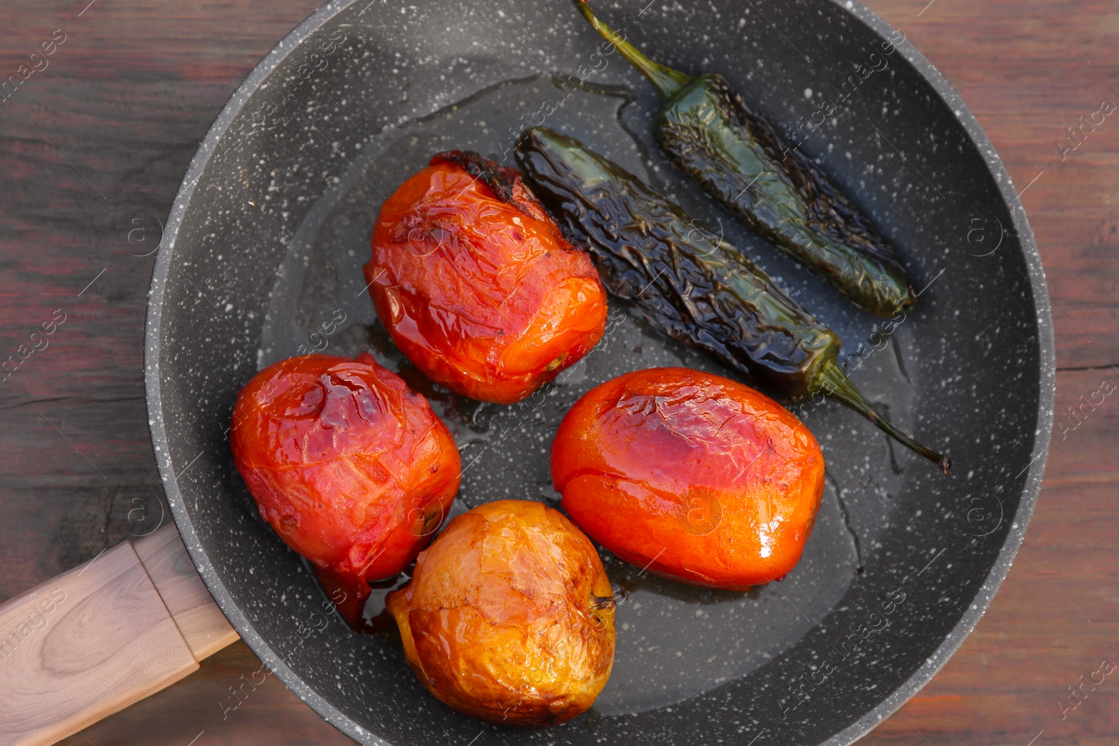 Photo of Frying pan with ingredients for salsa sauce on wooden table, top view