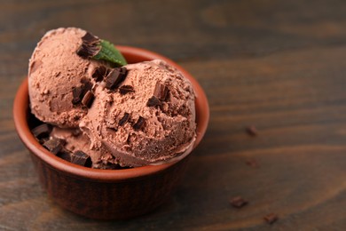 Photo of Bowl of tasty ice cream with chocolate chunks on wooden table, closeup. Space for text