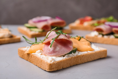 Delicious sandwiches with ham on grey table, closeup