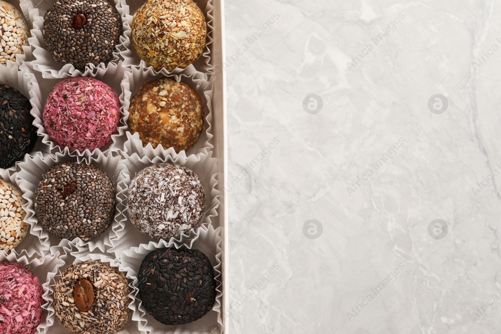 Photo of Different delicious vegan candy balls on light grey marble table, top view. Space for text