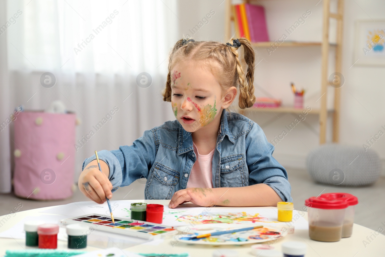 Photo of Cute little child painting at table in room