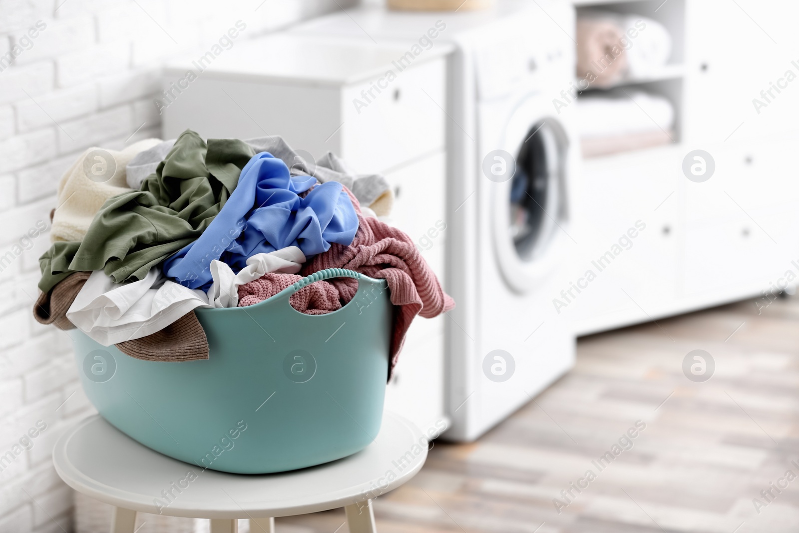 Photo of Plastic basket with dirty laundry indoors, space for text