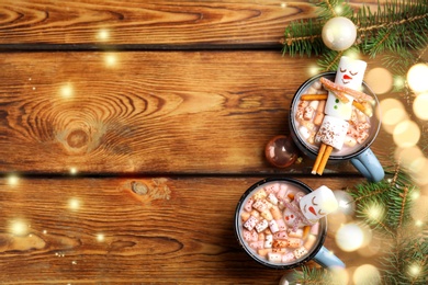 Image of Flat lay composition with marshmallow snowmen in cups of hot drinks on wooden table, space for text. Bokeh effect 