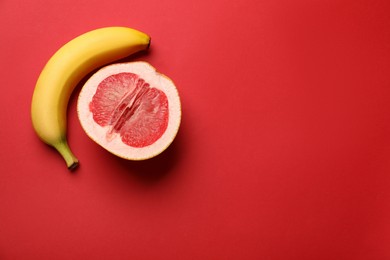 Photo of Banana and half of grapefruit on red background, flat lay with space for text. Sex concept