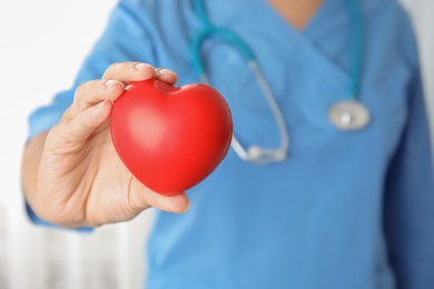 Photo of Doctor holding red heart in hand, closeup. Helping and supporting concept