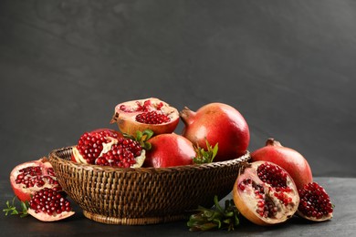 Delicious ripe pomegranates in bowl on black table