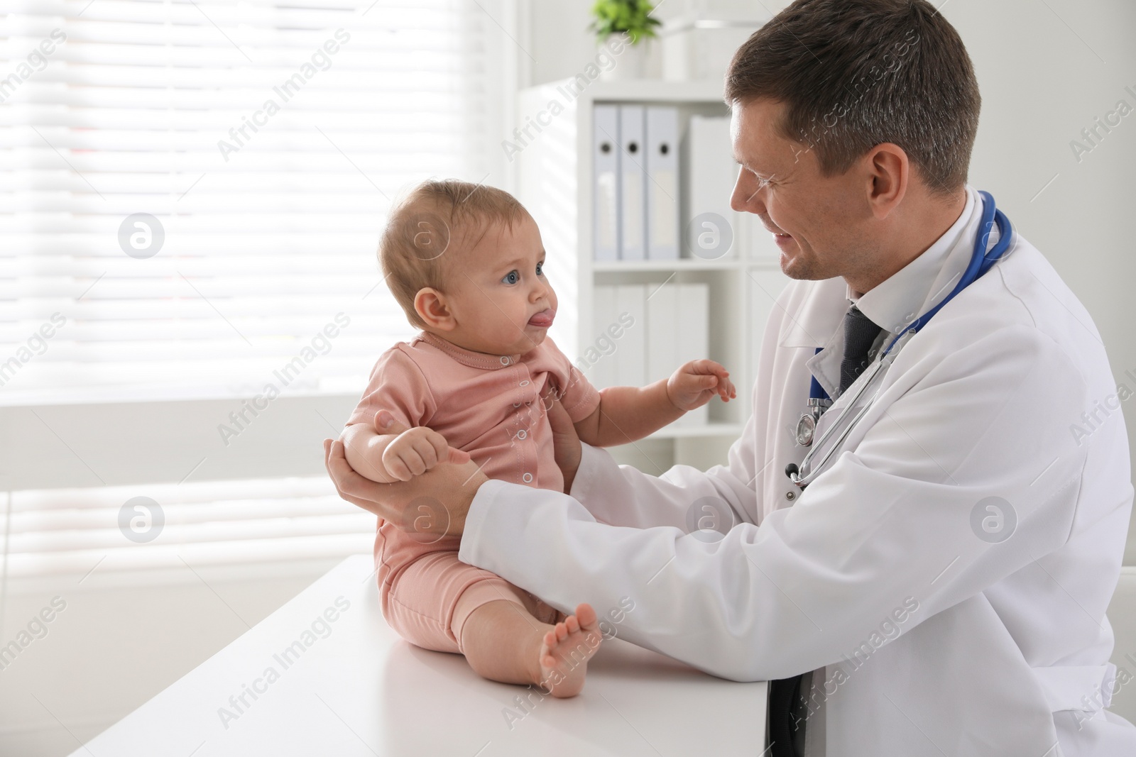 Photo of Pediatrician examining cute little baby in clinic