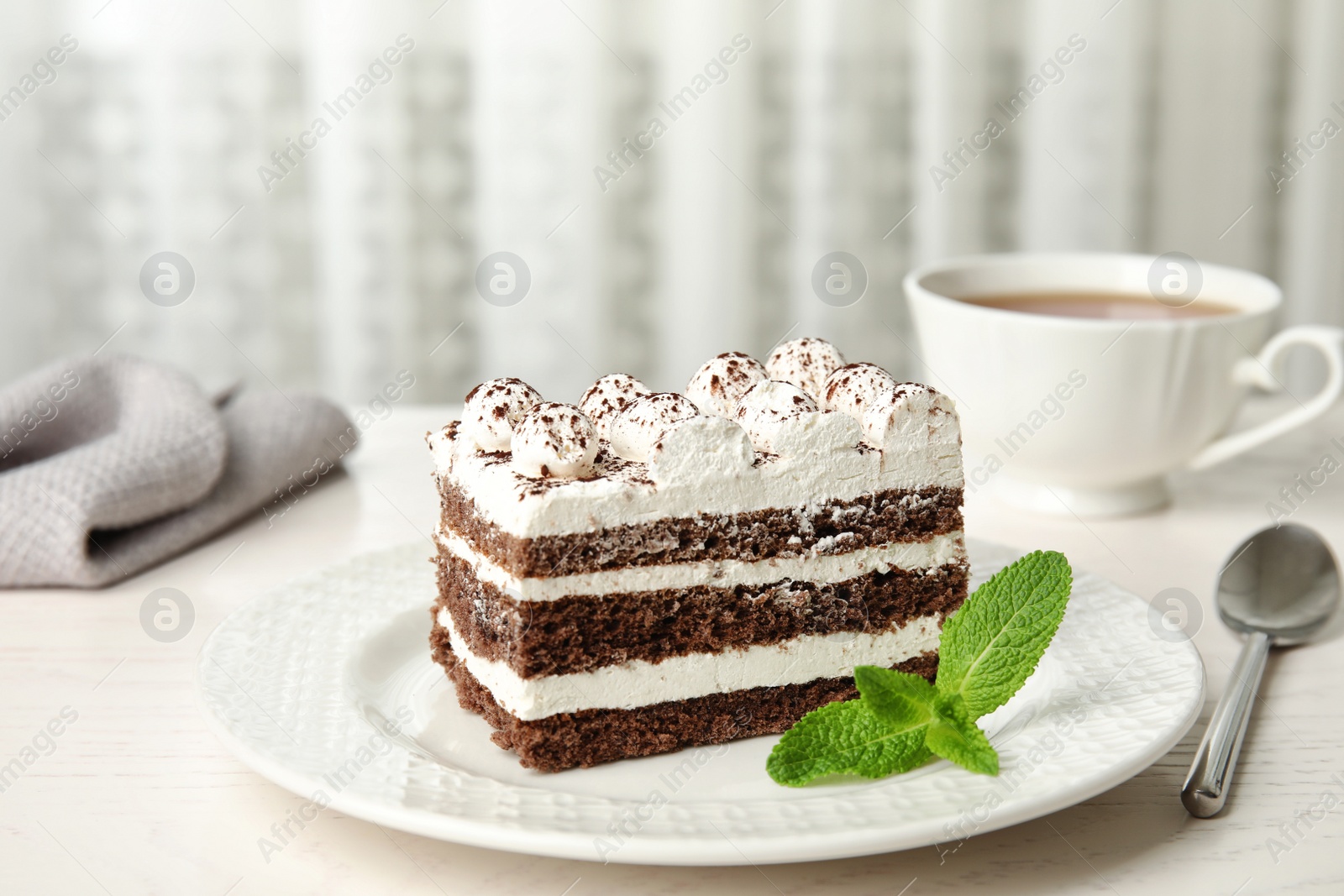 Photo of Tiramisu cake with cup on table against light background