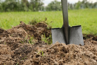 Photo of Shovel in soil outdoors, space for text. Gardening tool