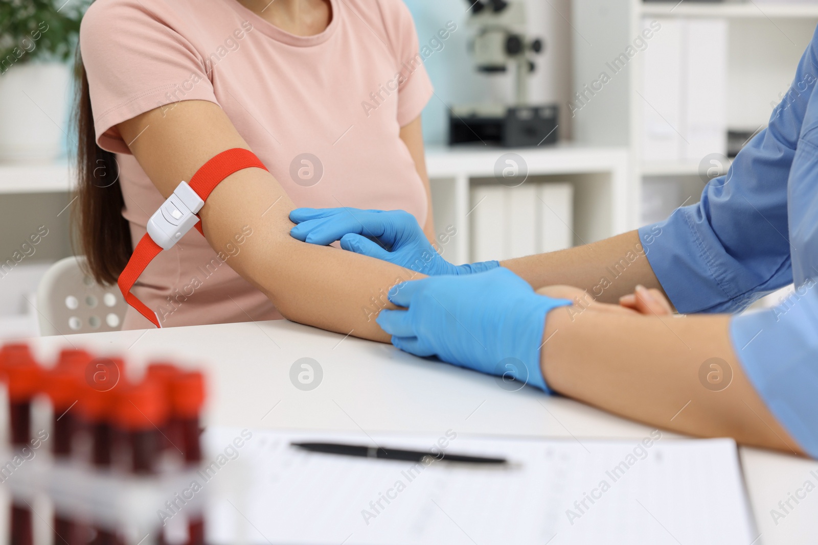 Photo of Laboratory testing. Doctor taking blood sample from patient at white table in hospital, closeup