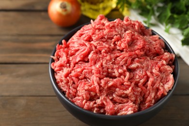 Photo of Raw ground meat in bowl on wooden table, closeup