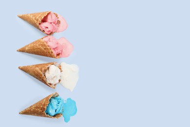 Photo of Melted ice cream in wafer cones on light blue background, flat lay. Space for text