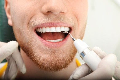 Photo of Professional dentist working with patient in modern clinic, closeup. Teeth care