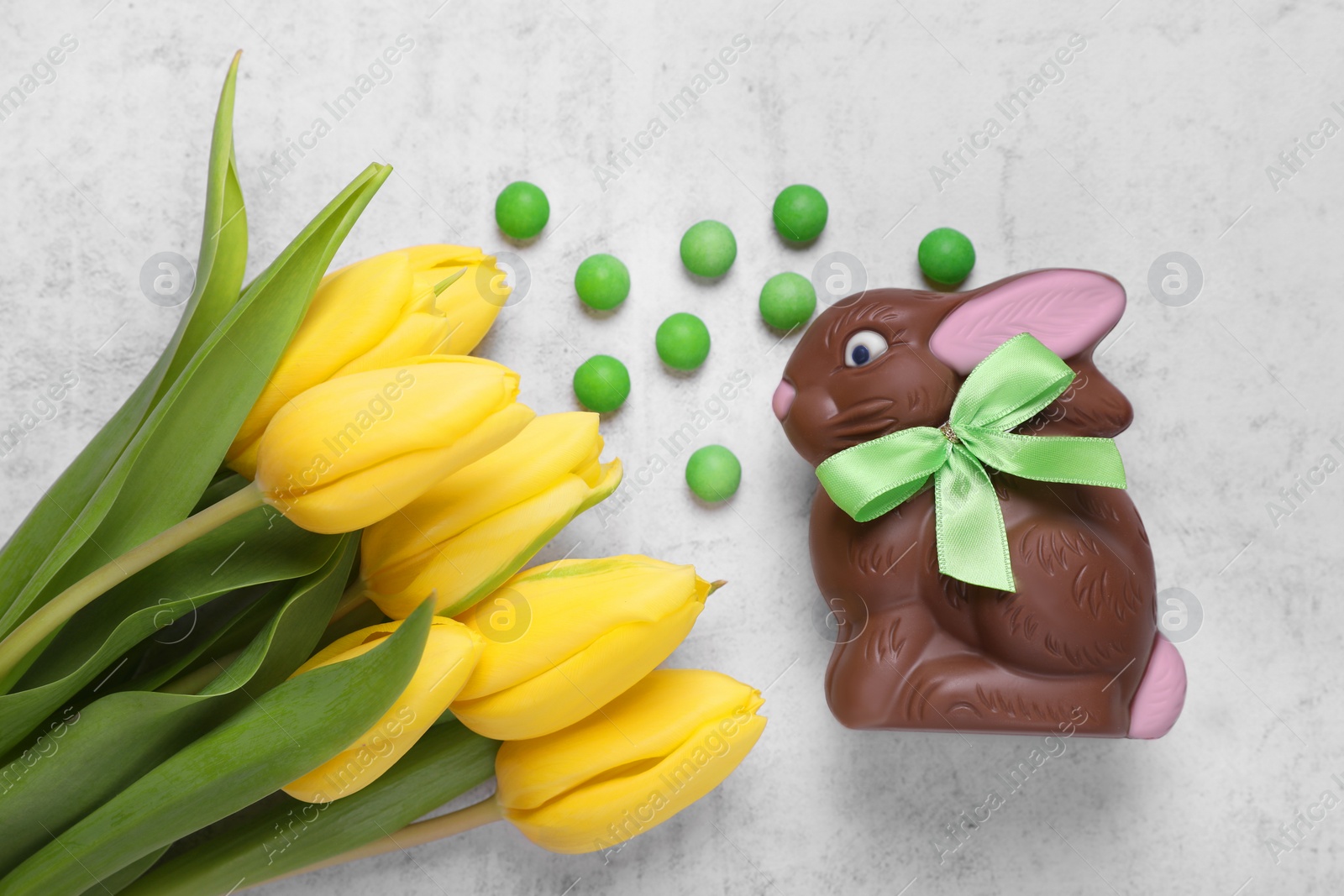 Photo of Flat lay composition with chocolate Easter bunny, beautiful tulips and candies on white textured table
