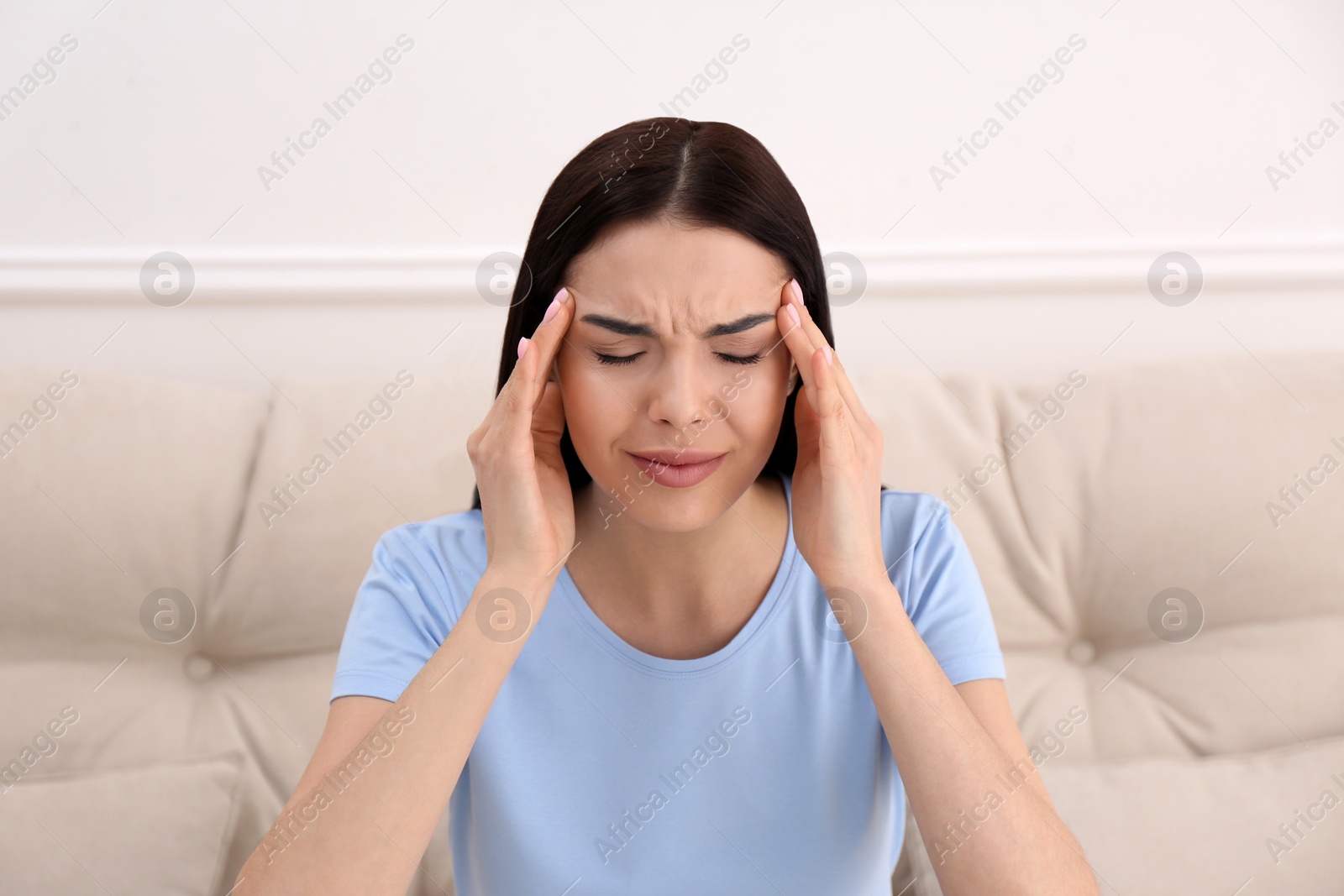 Photo of Young woman suffering from migraine at home