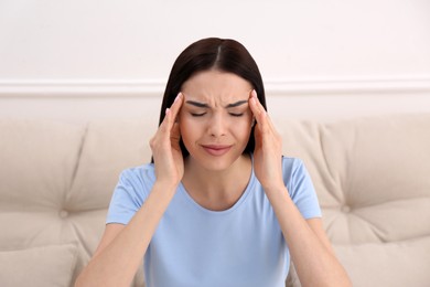 Photo of Young woman suffering from migraine at home