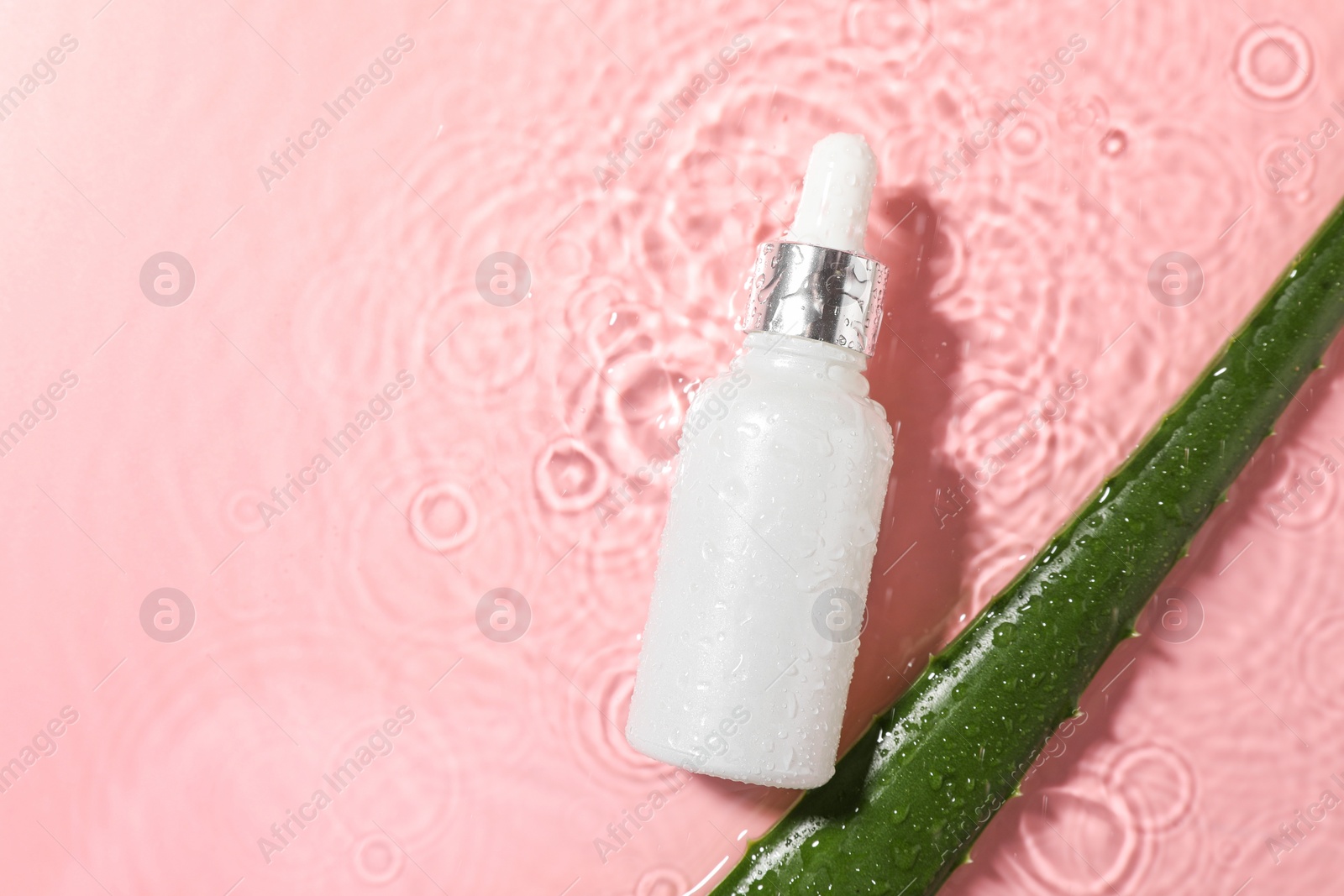 Photo of Bottle of cosmetic product and aloe leaf in water on pink background, flat lay. Space for text