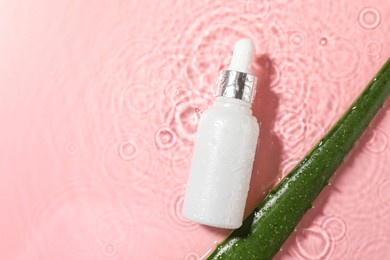 Bottle of cosmetic product and aloe leaf in water on pink background, flat lay. Space for text