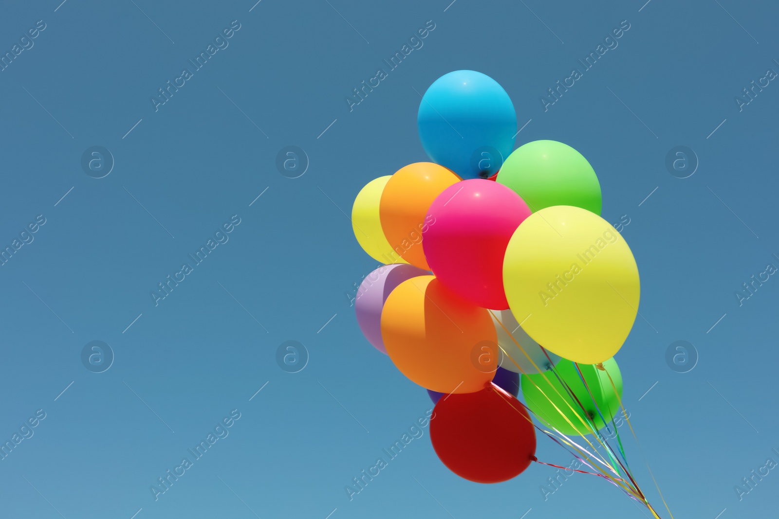 Photo of Bunch of colorful balloons against blue sky. Space for text