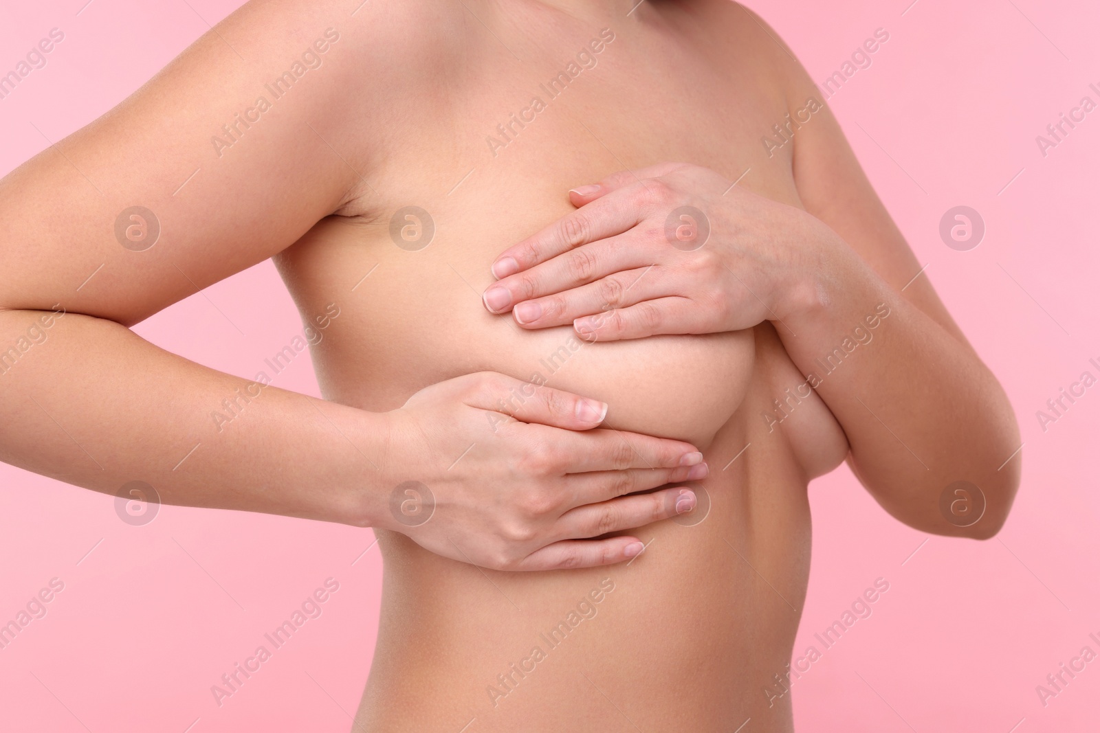 Photo of Mammology. Naked woman doing breast self-examination on pink background, closeup