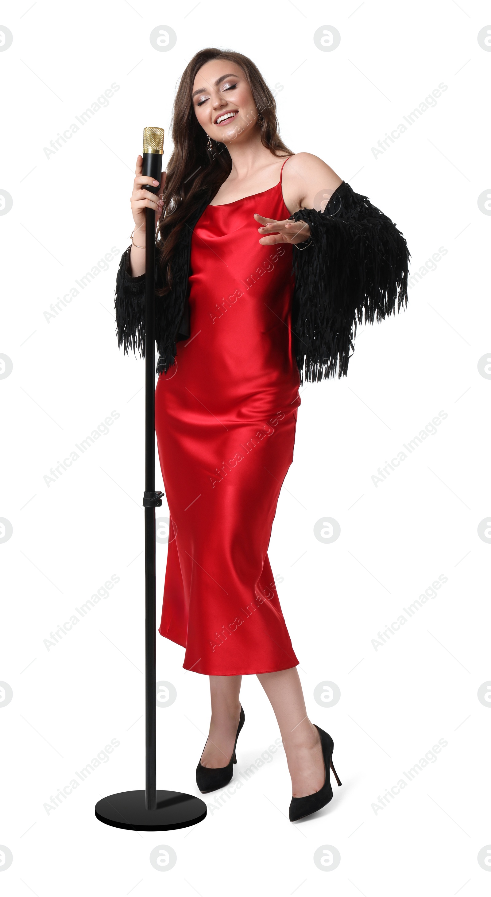 Photo of Beautiful young woman in stylish red dress with microphone singing on white background