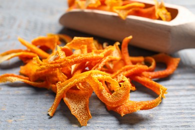 Photo of Scoop with dry orange peels on wooden table, closeup