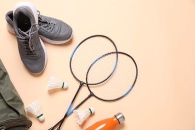 Photo of Badminton set, bag, sneakers and bottle on beige background, flat lay. Space for text