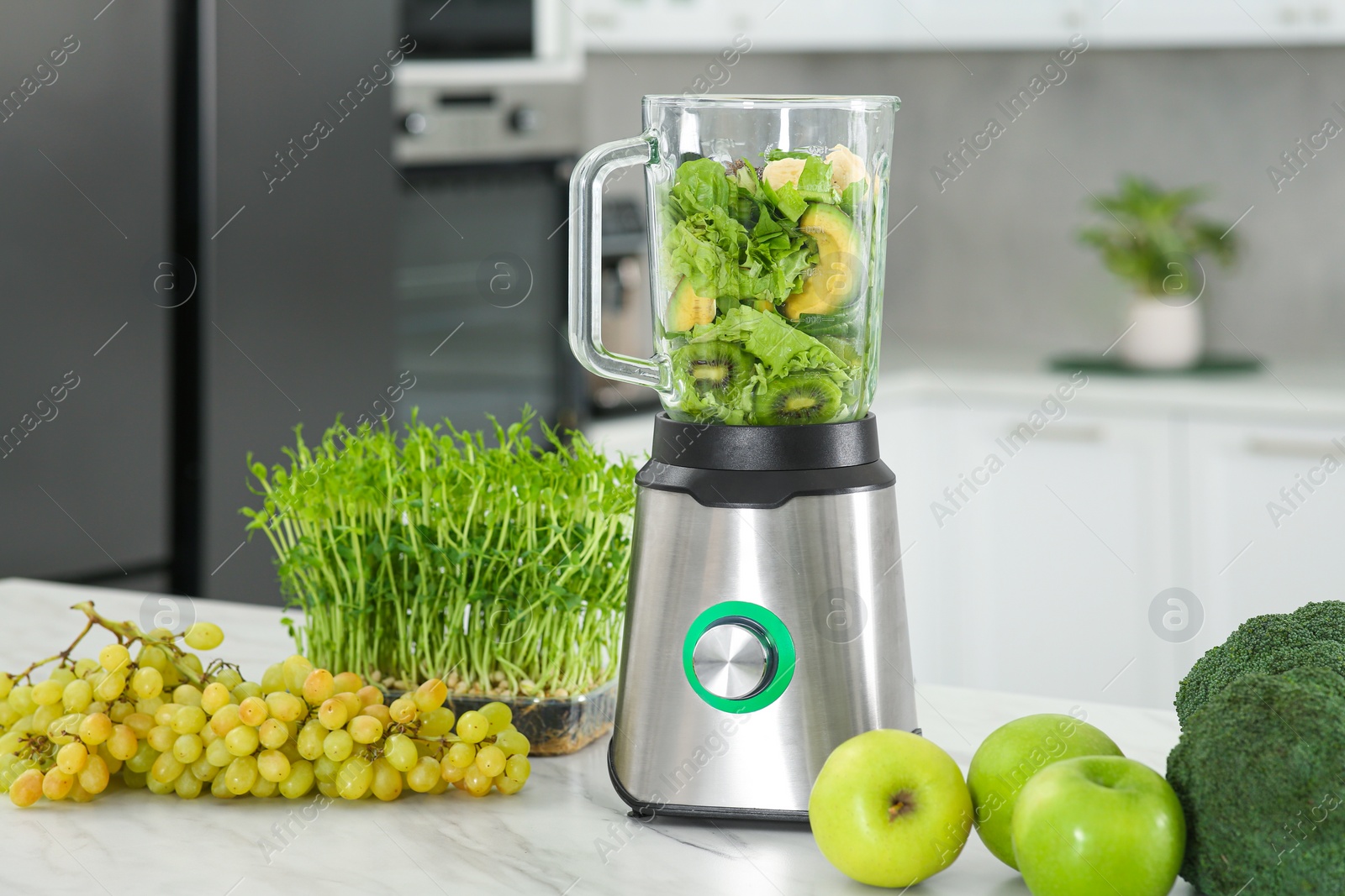 Photo of Blender with ingredients for smoothie and products on white marble table in kitchen