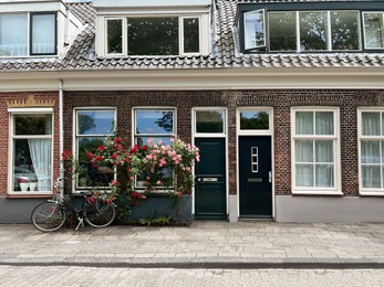 Photo of Beautiful building with blooming flowers and bicycle on city street