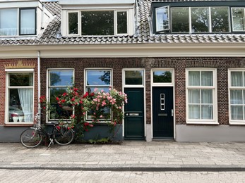 Beautiful building with blooming flowers and bicycle on city street