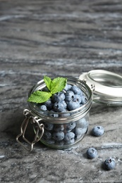 Photo of Jar with juicy and fresh blueberries on color table
