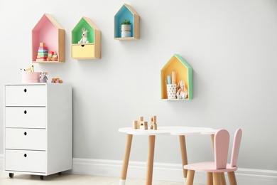 Photo of Children's room interior with house shaped shelves and little table