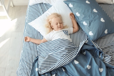 Photo of Cute little girl sleeping in bed at home, view from above