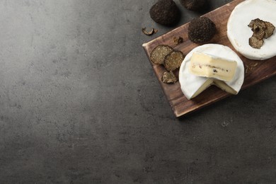 Delicious cheeses and fresh truffles on grey table, flat lay. Space for text