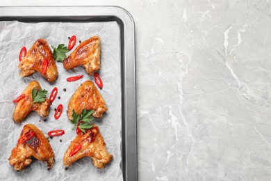 Photo of Tray with delicious fried chicken wings on light gray marble table, top view. Space for text