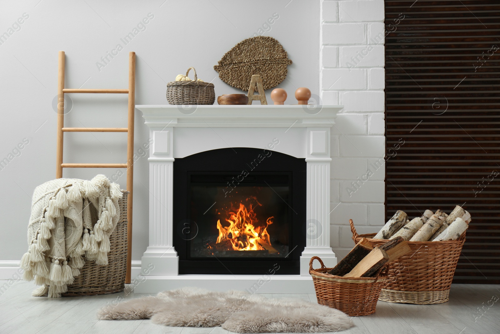 Photo of Wicker baskets with firewood and white fireplace in cozy living room