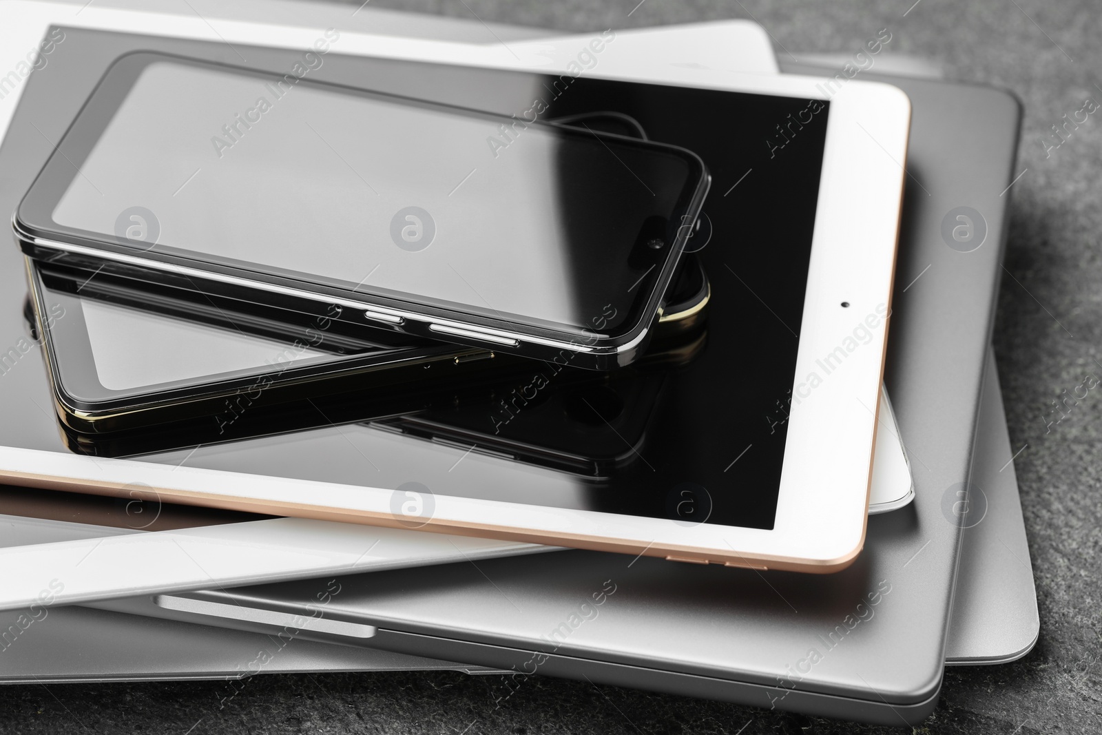 Photo of Stack of electronic devices on grey table, closeup