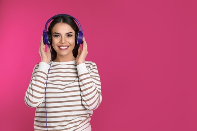 Photo of Attractive young woman enjoying music in headphones on color background. Space for text